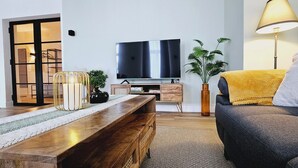 A living room with a wooden coffee table, a sofa, a TV, a lamp, and a plant.
