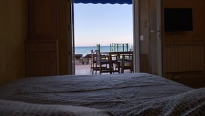 Una habitación con cama, vistas a la playa y una mesa con sillas afuera.