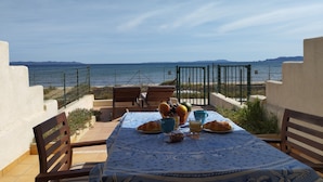 Mesa con comida y bebidas, con vistas al mar y una cerca con sillas.