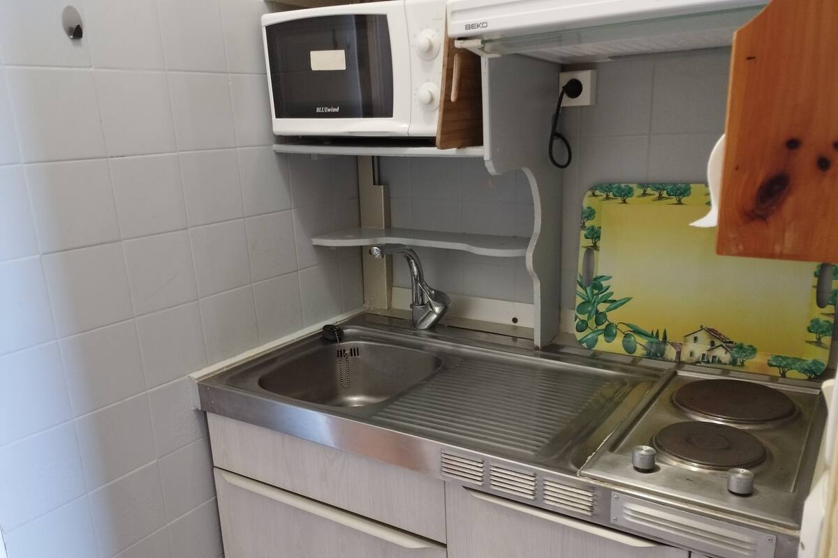 A compact kitchenette with a sink, a microwave, and a stove.