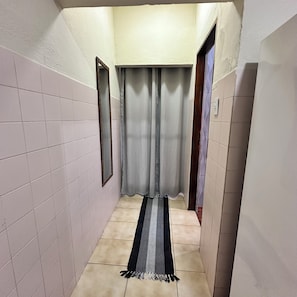 A narrow hallway with tiled walls, a striped rug, and a door on the right. - Mary's mantle house (Aparecida)
