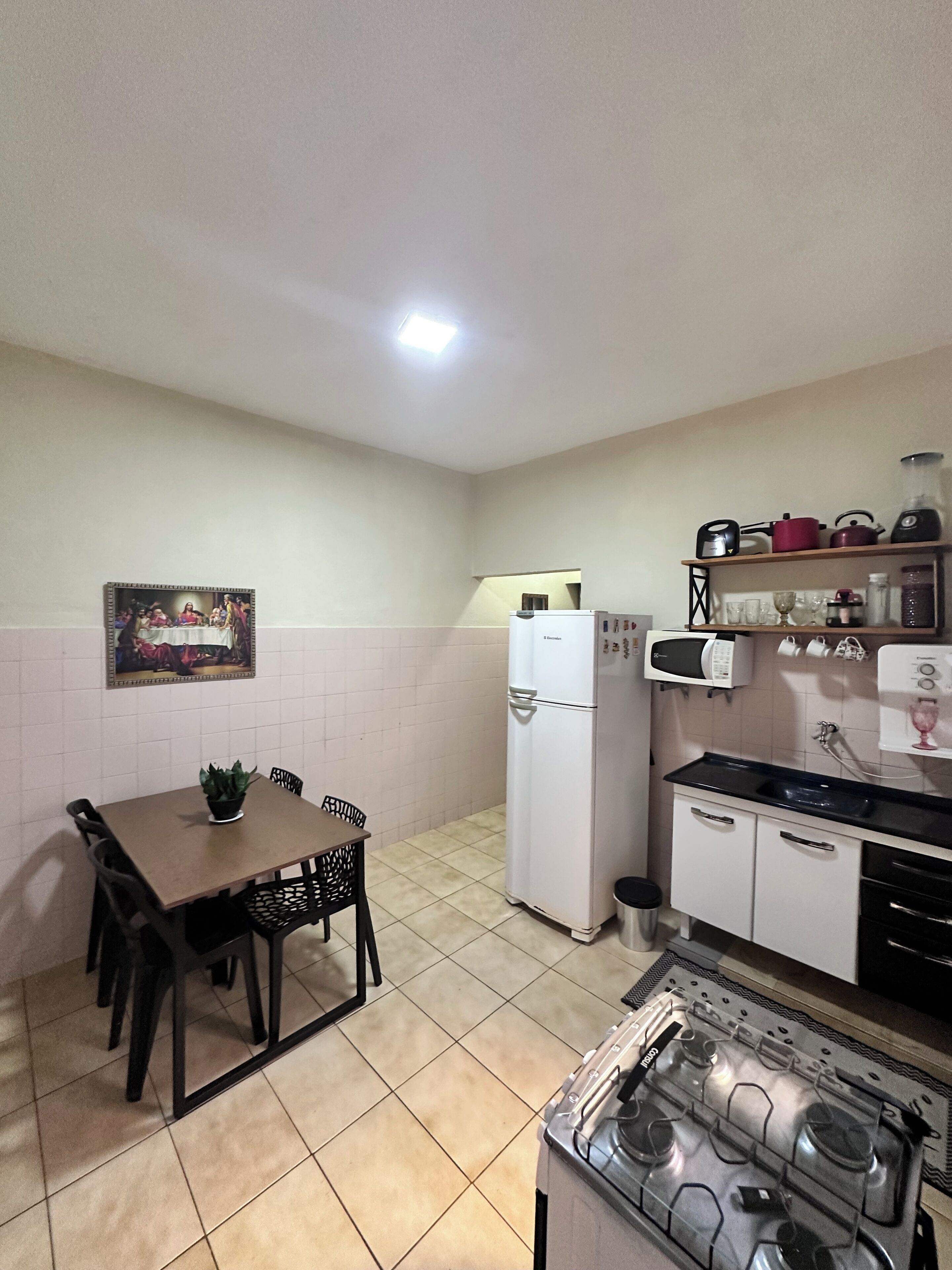 Una cocina compacta con una mesa de comedor, sillas, un refrigerador, una estufa y un microondas.