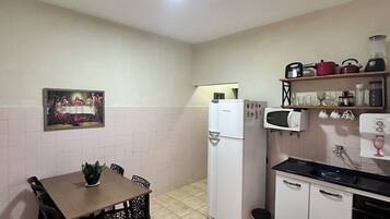 Una cocina compacta con una mesa de comedor, sillas, un refrigerador, una estufa y un microondas.