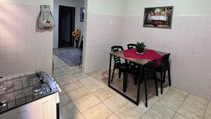 A kitchen with a gas stove, a dining table with chairs, and a wall-mounted picture.