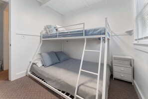 A bunk bed with a ladder, a bedside table, and a small drawer unit. - Sea Glass (Wells)