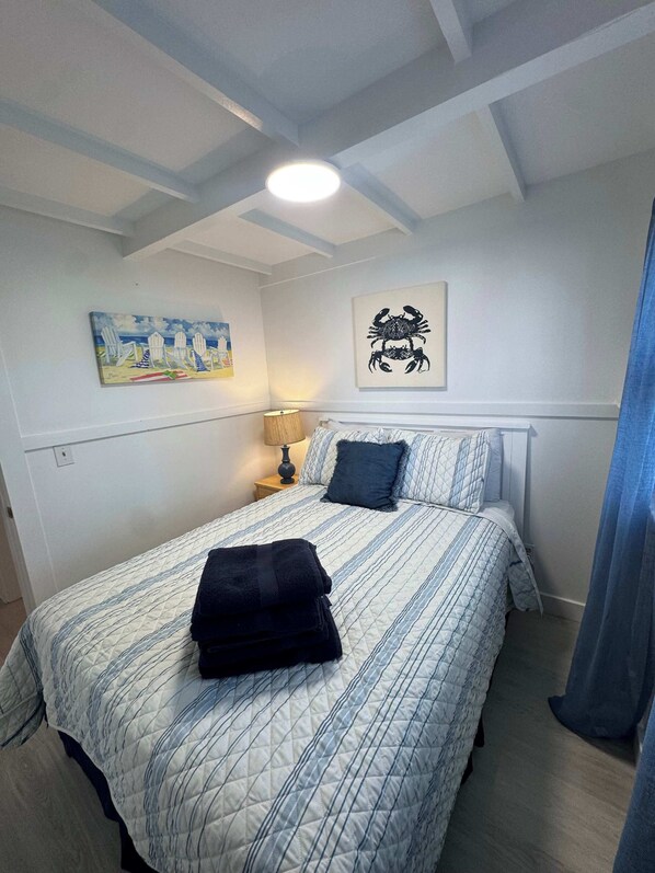 A bedroom with a bed, a nightstand, a lamp, and two wall art pieces.