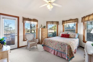 Une chambre à coucher comprenant un lit, une chaise, une commode et un ventilateur de plafond.