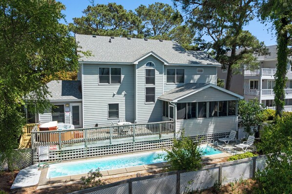 Une maison à deux étages dotée d’une piscine, d’un patio couvert et d’une terrasse délimitée par une clôture.