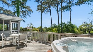 Una terraza de madera con mobiliario exterior y un jacuzzi.