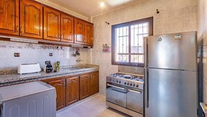Une cuisine dotée de meubles en bois, d’un réfrigérateur en acier inoxydable, d’une cuisinière à gaz et d’un four encastré.