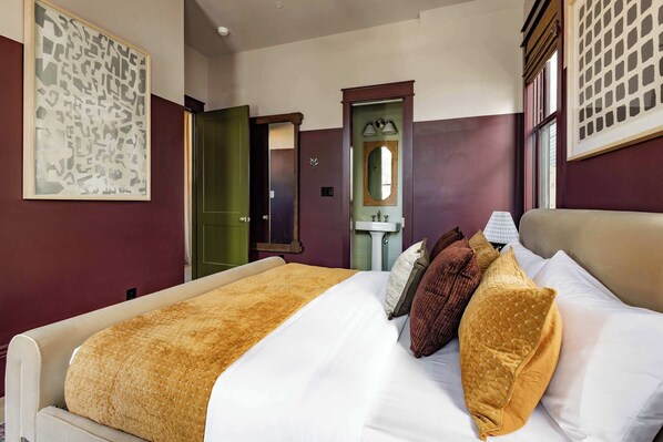 Una habitación de hotel con cama, espejo, ventana y puerta.