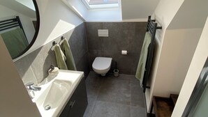 Une petite salle de bain avec un puits de lumière, des toilettes, un lavabo et un miroir.