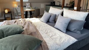 Une chambre avec un grand lit, un bureau et une chaise. Il y a une lucarne au-dessus du bureau.
