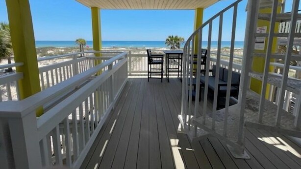 A wooden deck with a railing, a table, and chairs, overlooking a beach. - "The Sandy Turtle" Beachfront bungalow, pet friendly Sleeps 8 (Eastpoint)