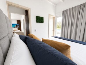 Ein modernes Hotelzimmer mit einem großen Bett, einer Couch und Blick ins Freie.