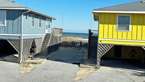 A beachside building with a wooden staircase leading to a sandy path.