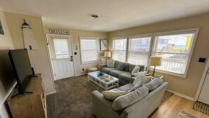 A living room with a sofa, coffee table, TV, and windows.