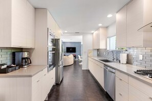 Une cuisine moderne dotée d’un coin café, d’appareils électroménagers en acier inoxydable et donnant sur un espace de vie.