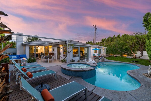 A modern house with a swimming pool, outdoor seating, and a hot tub.