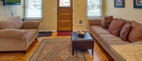 A living room with two sofas, a coffee table, a rug, and a door.