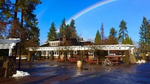 A building with a covered patio area, surrounded by trees and a clear sky. - Bluebird Day - Twin Mills Bungalow in Bend, OR, featuring 2 cozy bedrooms. (Bend)