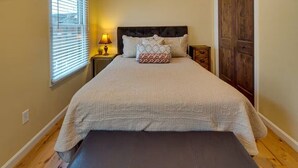 A bedroom with a bed, a bedside table with a lamp, a wooden wardrobe, and a bench. - Bluebird Day - Twin Mills Bungalow in Bend, OR, featuring 2 cozy bedrooms. (Bend)