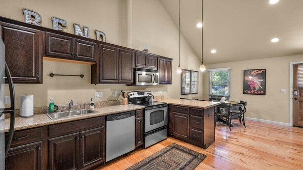 A spacious kitchen with dark wooden cabinets, stainless steel appliances, and a large island. - Bluebird Day - Sierra Nook, one-bedroom retreat in Bend, ideal for couples and pet-friendly. (Bend)