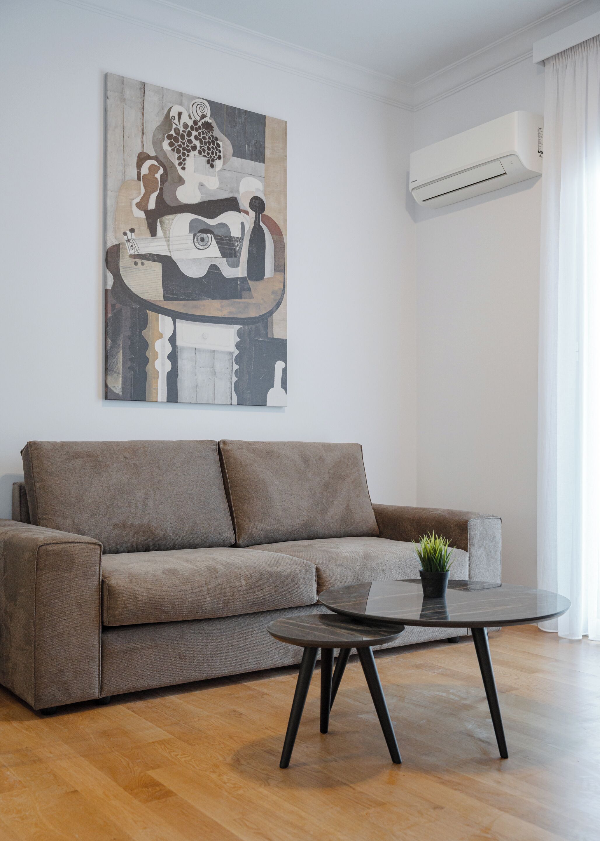 Una sala moderna con un sofá gris, una mesa de centro y un cuadro en la pared.