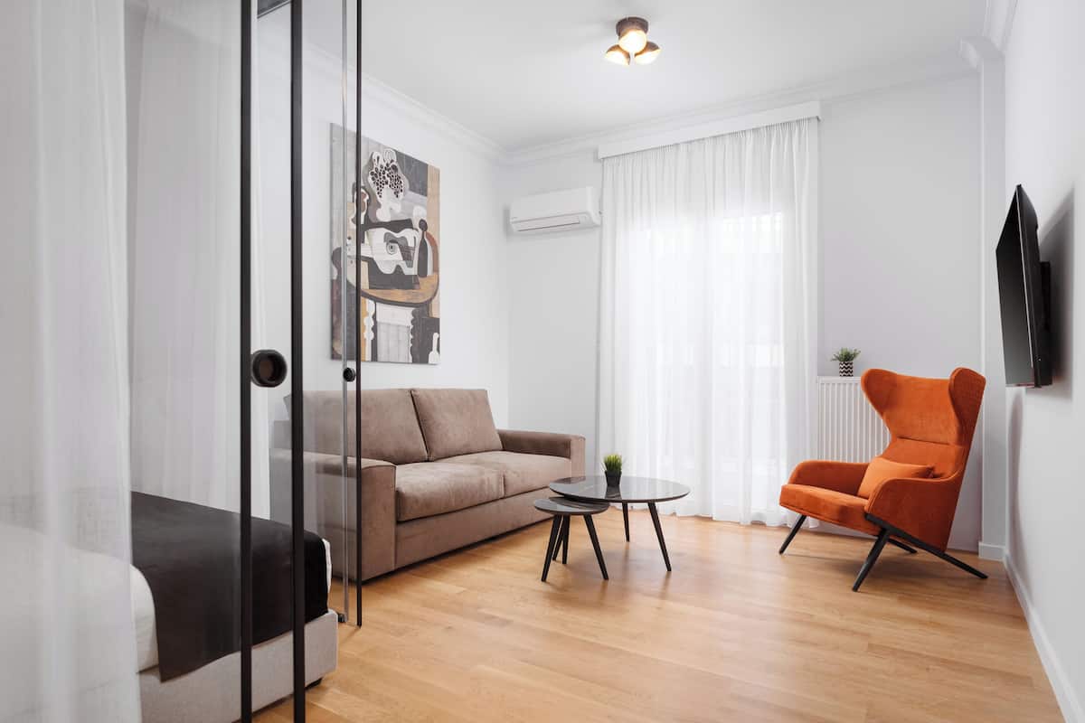 Un salon moderne avec un canapé, une table basse et un fauteuil orange.