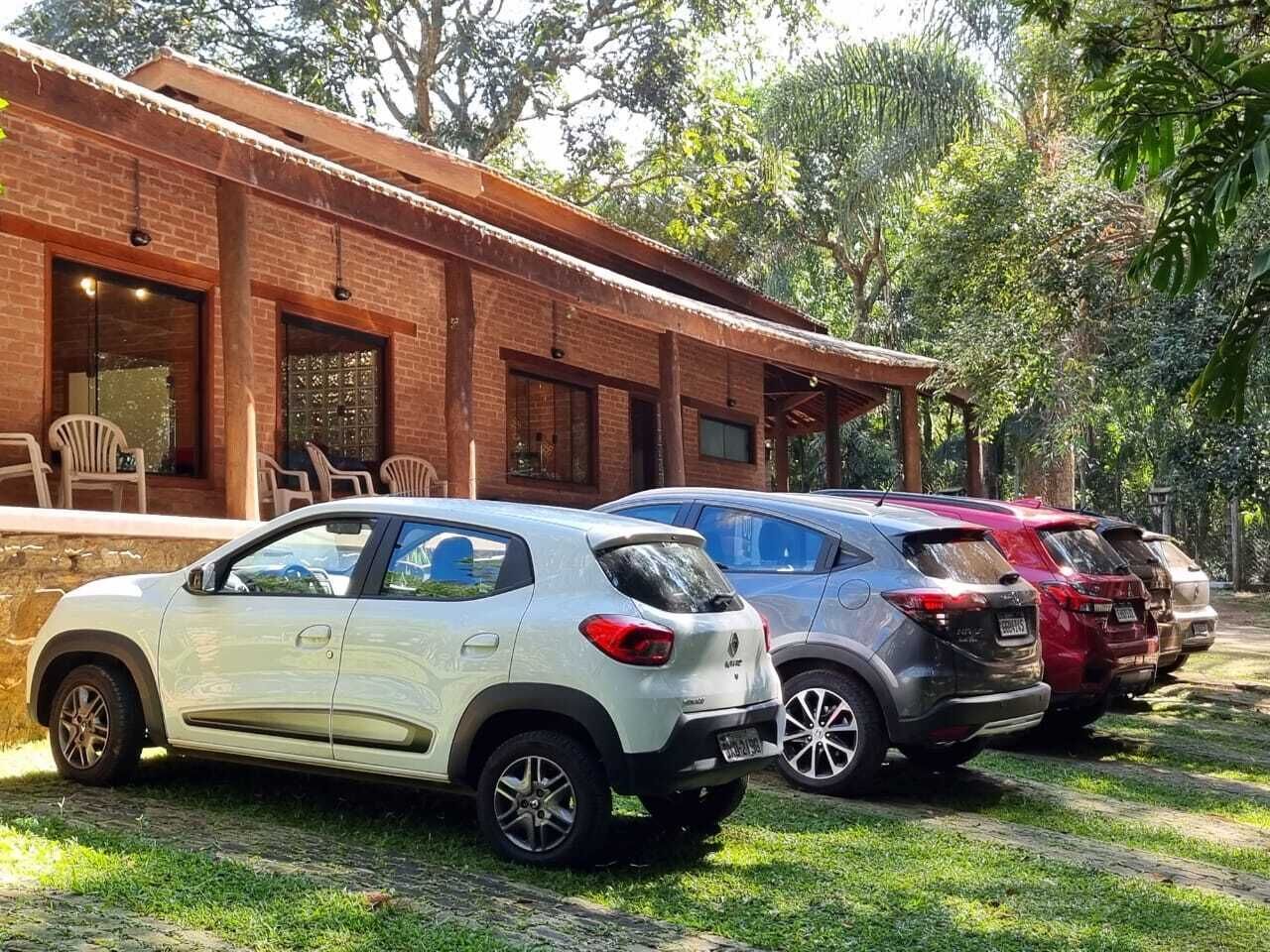 A brick building with a covered outdoor seating area and three parked cars.