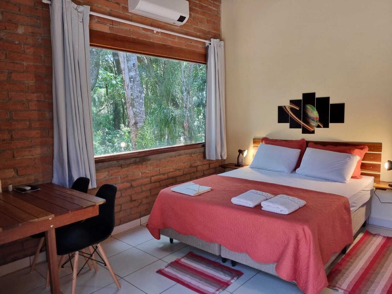 A room with a bed, a desk, and a window with curtains.
