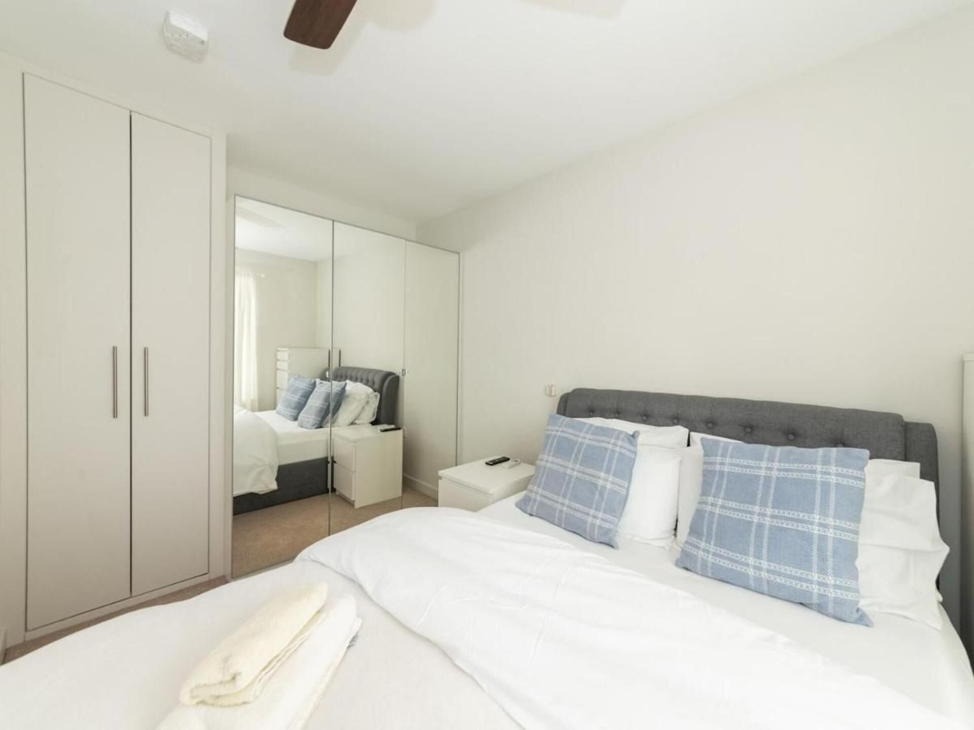 Een slaapkamer met een bed, nachtkastje, kledingkast en spiegel.