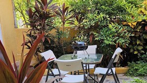 An outdoor patio with a round table and four chairs, surrounded by various plants and greenery. - Luxury on stunning La Ropa beach in tropical Zihuatanejo Mexico (Zihuatanejo México)