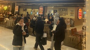 En Burger King restaurant med et moderne interiør, herunder et højtloft med lineære lysarmaturer og et siddeområde med borde og stole.