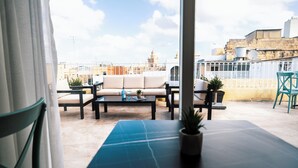 Een dak terras met een bank, salontafel en stoelen, met uitzicht op een stadsbeeld met gebouwen en een moskee.