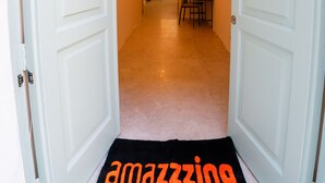Een gang met witte deuren, een zwart tapijt met de tekst 'amazing' en een trap op de achtergrond.