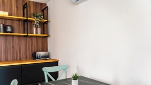 Een moderne keuken met houten lambrisering, een zwart aanrecht, een broodrooster en twee lichtblauwe stoelen.