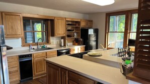 Una cocina moderna con armarios de madera, un refrigerador negro y un ventanal que proporciona luz natural.