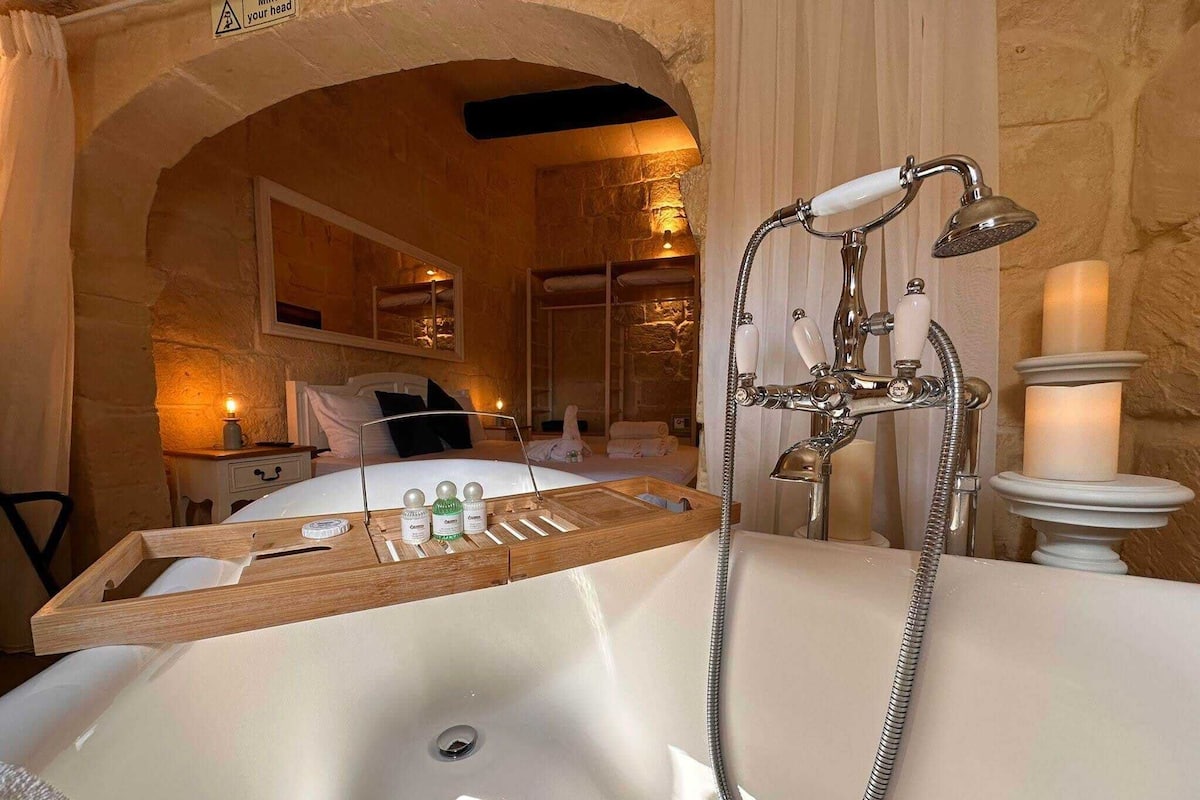 A bathroom with a large bathtub, a shower, and a wooden tray with toiletries.