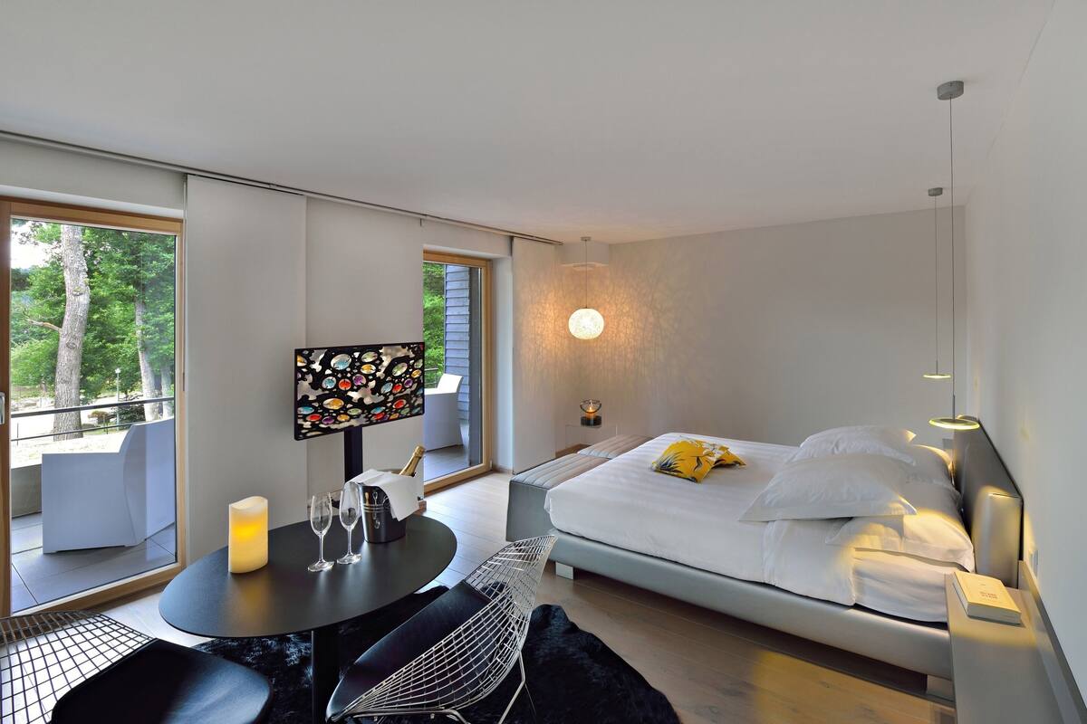 Un dormitorio moderno con cama, mesita de noche y televisor sobre un mueble.