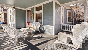 A covered porch with wicker furniture and a ceiling fan.