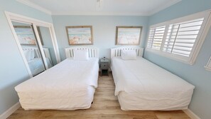 Habitación doble con dos camas individuales, una mesita de noche pequeña y una ventana con persianas.