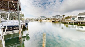 A marina with boats docked, a wooden pier, and waterfront houses.