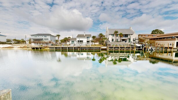 A waterfront property with multiple buildings, a dock, and a calm body of water reflecting the structures.