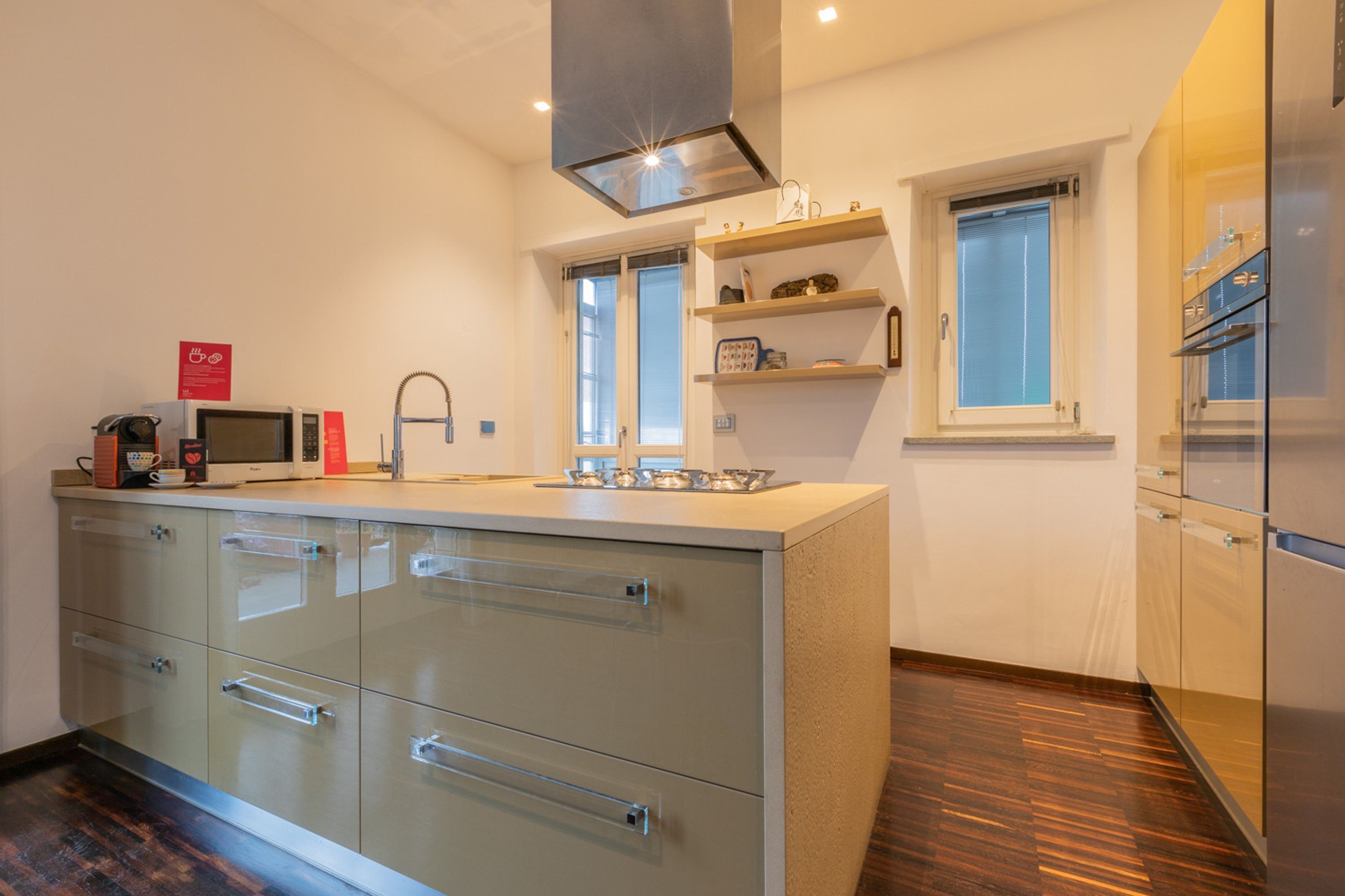 Cozinha moderna com ilha central, eletrodomésticos de aço inoxidável e piso de madeira.