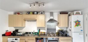 Una cucina compatta con lavastoviglie, forno e microonde. Ci sono pensili sopra il bancone e un frigorifero decorato con calamite.