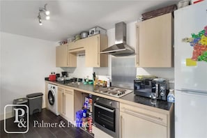 A modern kitchen with light wood cabinets, stainless steel appliances, a built-in oven, and a microwave.