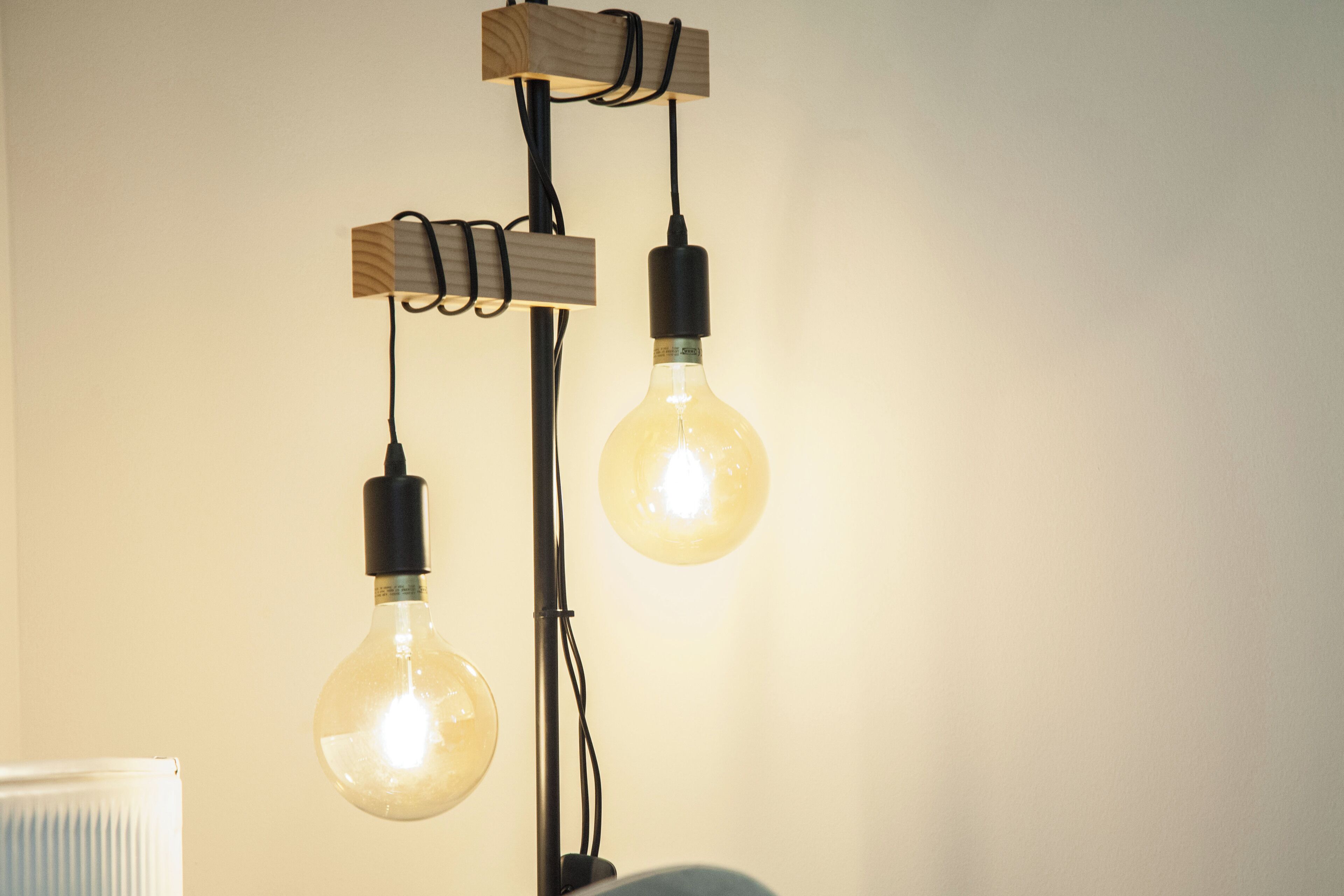 A modern light fixture with two exposed bulbs hanging from wooden brackets.