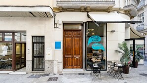 A cafe with a wooden door, outdoor seating, and a sign advertising 'Joueries de Delicieux Dessert'.