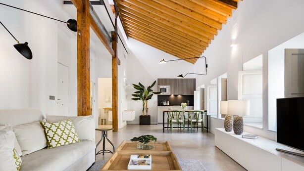A modern living room with a sofa, coffee table, and a TV on a white cabinet.